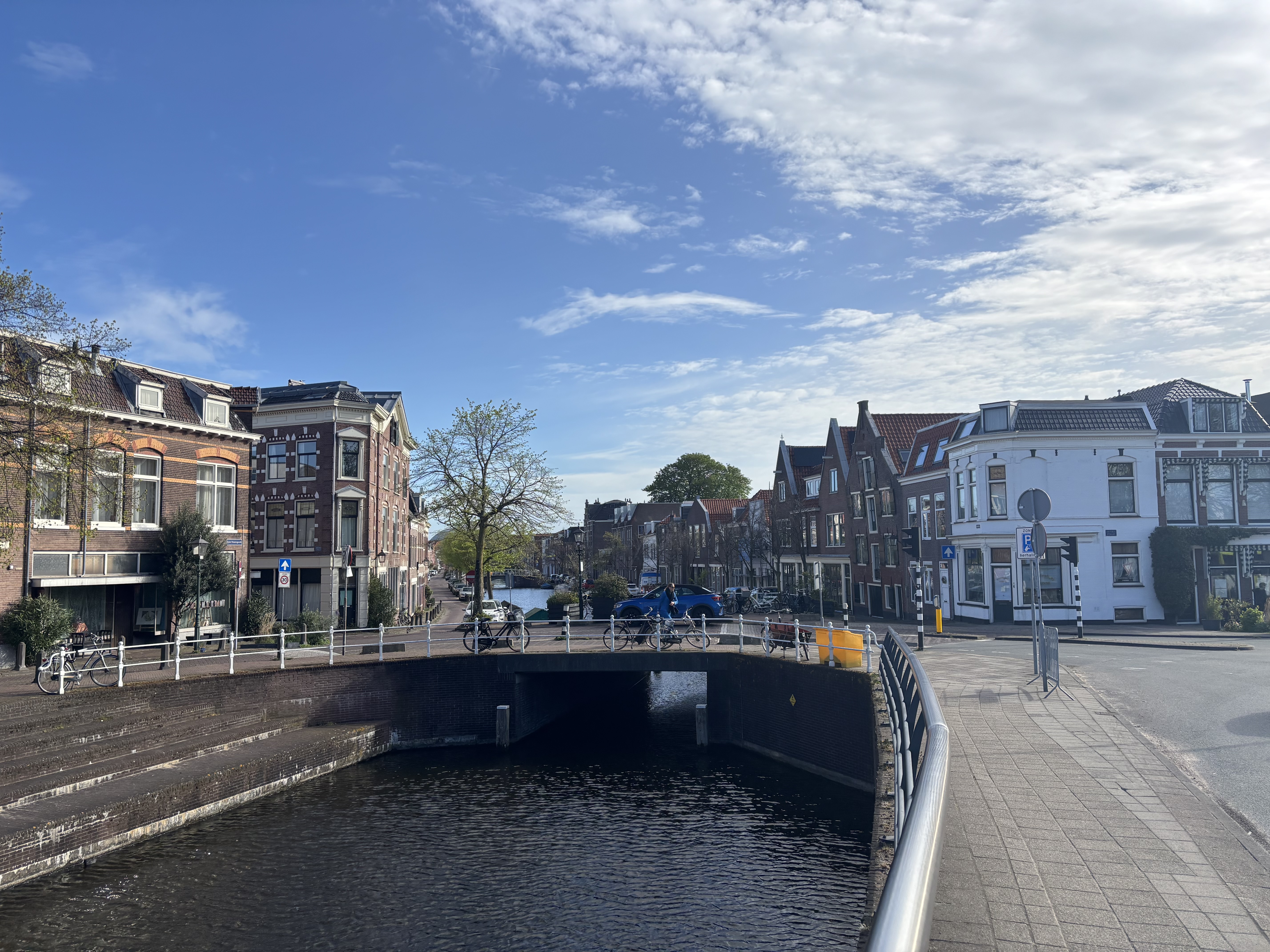 A small canal bridge in a classic Dutch town — bicycles parked along the railing, gabled houses lining the street.